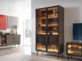 Beleuchteter Vitrinenschrank mit Gläsern und Dekoartikeln, daneben ein Sideboard.