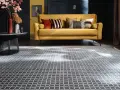 Ein gelbes Sofa mit Kissen steht auf einem gemusterten Teppich unter dem Sofa.