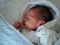 Neugeborenes Baby schläft friedlich, eingewickelt in eine Decke. Der sanfte "white noise" des Geräuschs hilft ihm beim Einschlafen.
