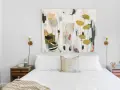 Modernes Schlafzimmer renovieren: Weißes Bett mit Kissen, Nachttisch und abstraktem Gemälde über dem Kopfende.