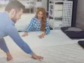 Ein Paar prüft im Matratzengeschäft, wie oft man eine Matratze wechseln sollte, und fühlt die verschiedenen Modelle.