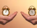 Zwei Hände halten je einen Wecker. Die Frage ist: wann aufstehen?