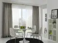 Ein Essbereich mit einem runden Tisch, vier Stühlen und einem Fenster, das von einer Gardinenschiene oder Stange mit grauen und weißen Vorhängen eingerahmt wird.