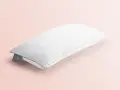 Ein weißes, wabenförmiges Kopfkissen liegt auf einem zartrosa Hintergrund. Perfekt für das Kopfkissen waschen, um Frische zu garantieren.