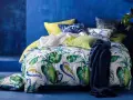 Ein tropisch gemustertes Bett mit Kissen in Blau und Grün. Für ein frisches Gefühl: wie oft Bettdecke wechseln?