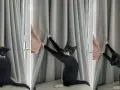 Eine schwarze Katze mit weißen Pfoten klettert an einer grauen Gardine hoch und hinterlässt Spuren.