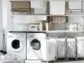 Wäscheständer mit Haken für Gardinen, zwei Waschmaschinen, Wäschekörbe und sauber gefaltete Handtücher.