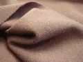 Braune Stofffalten, die die glatte, feine Struktur von Single Jersey zeigen. Dieses Material ist weich und dehnbar.
