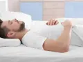 Mann schläft auf dem Rücken, Kopf auf einem Kissen gebettet. Die richtige Schlafposition mit dem passenden Kissen ist wichtig für erholsamen Schlaf.