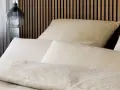 Gemütliches Bett mit Kissen und Decken im dezenten **muster paisley**. Ein moderner Nachttischlampen-Pendel hängt daneben.
