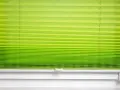 Grünes Plissee zu lang, schlimm. Die Falten sind eng und gleichmäßig, die Farbe verläuft von hellgrün zu einem kräftigeren Ton.