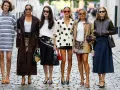 Sechs Frauen in stylischen Outfits, darunter ein gestreiftes Kleid und ein Blazer mit nordischen Mustern, posieren auf einer Kopfsteinpflasterstraße.