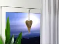 Holzherz hängt an einer Schnur, um die Gardinenstange zu dekorieren. Grüne Blätter und ein dramatischer Himmel im Hintergrund.