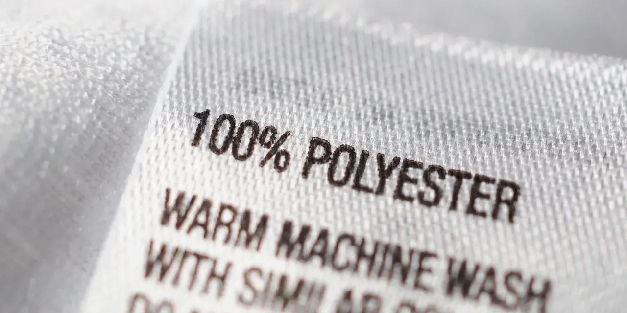 Etikett zeigt "100% POLYESTER". Dieser Stoff ist pflegeleicht und ideal für Kleidung, die oft gewaschen wird.
