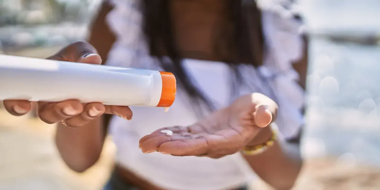 Frau gibt Sonnencreme auf ihre Hand. So vermeidet sie Sonnencreme Flecken auf Kleidung.