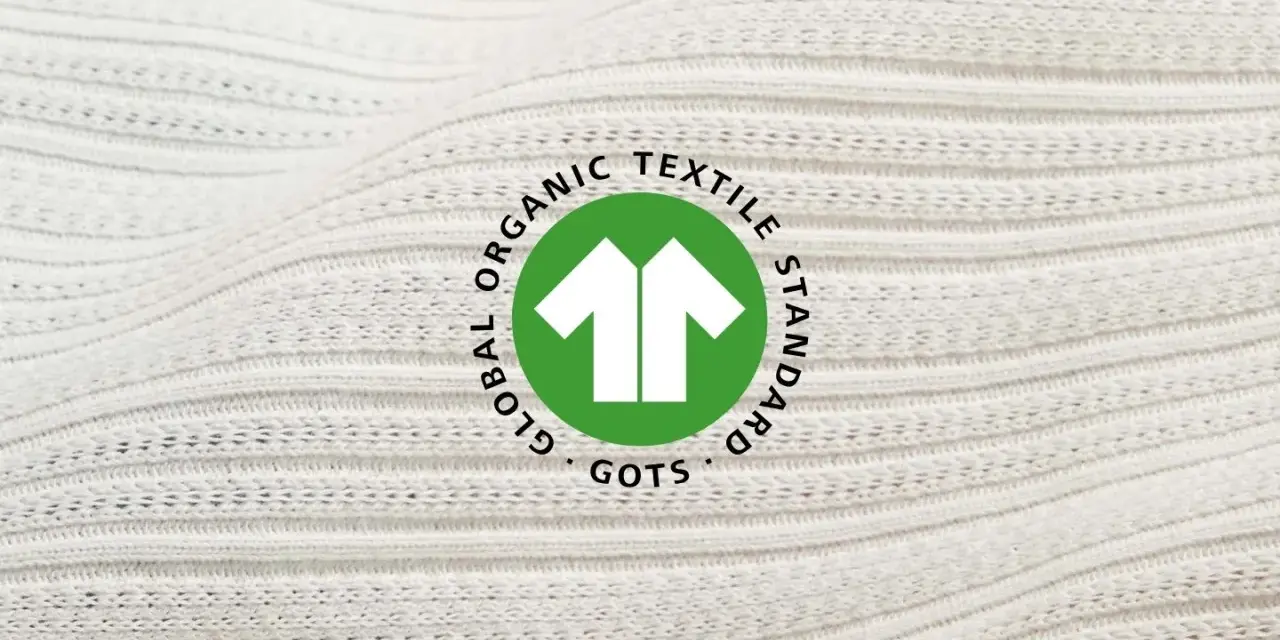 Das GOTS-Zertifikat auf weißem, geripptem Stoff. Es steht für Global Organic Textile Standard und garantiert nachhaltige Textilien.