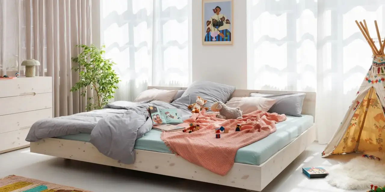 Ein gemütliches Familienbett mit Spielzeug und Kuscheltieren, das zum Kuscheln einlädt. Hier ist Platz für die ganze Familie.