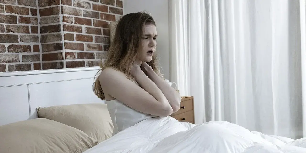 Junge Frau im Bett, die sich die Kehle hält, als ob das **Bett quietscht** und sie stört.