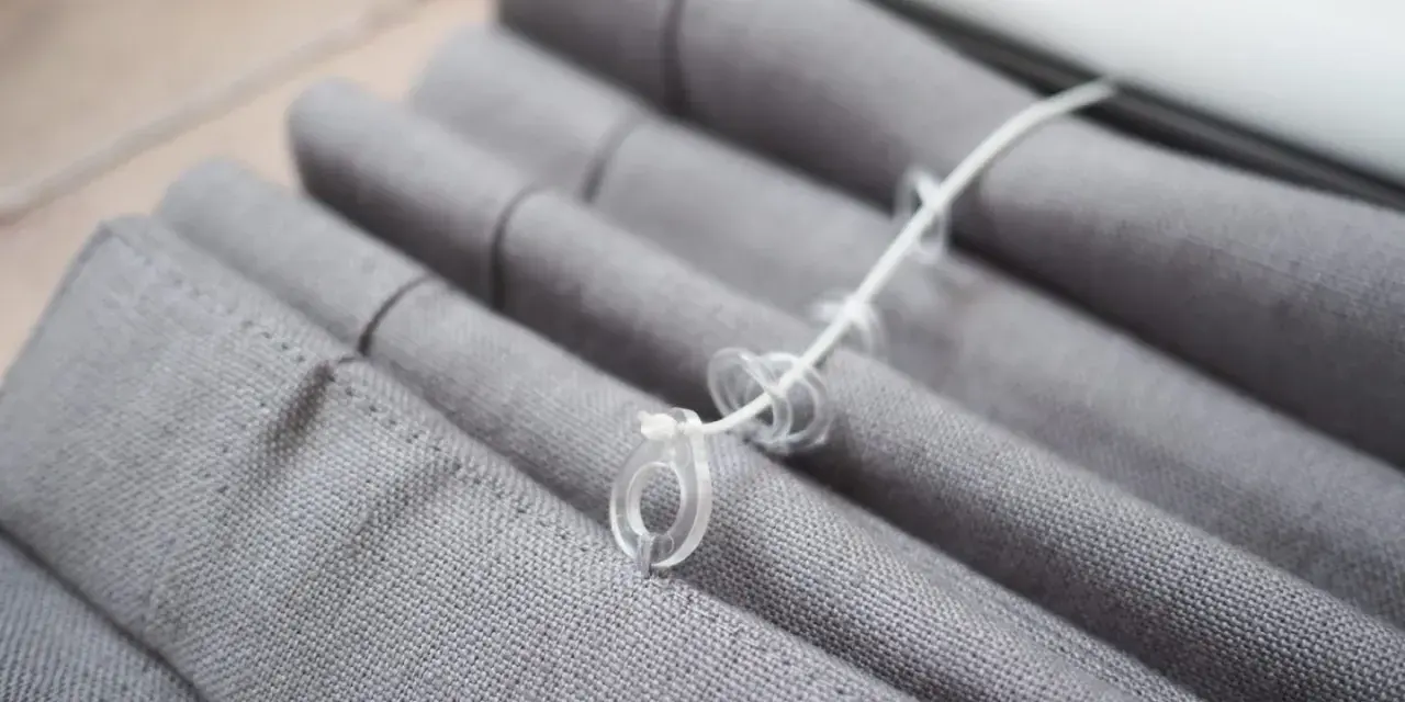 Grauer Raffrollo Stoff mit Schnüren und Ringen, bereit zum Raffrollo waschen.