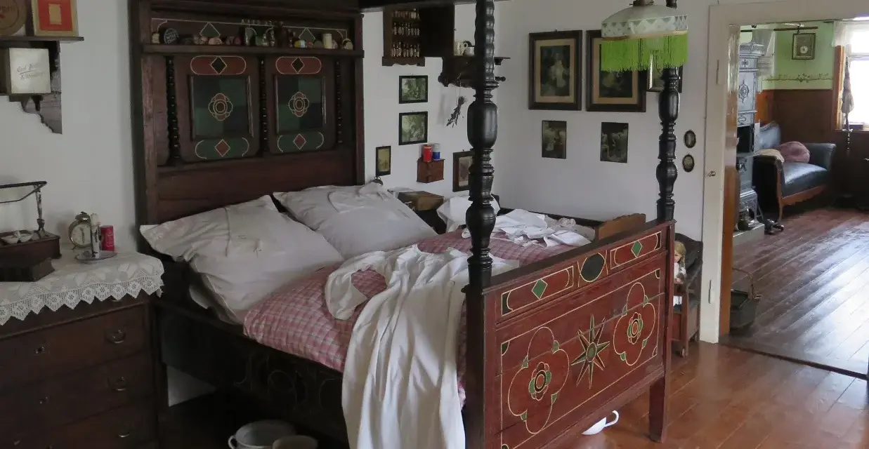 Ein prachtvolles Himmelbett im mittelalterlichen Stil, mit kunstvollen Schnitzereien und einem karierten Bettzeug.