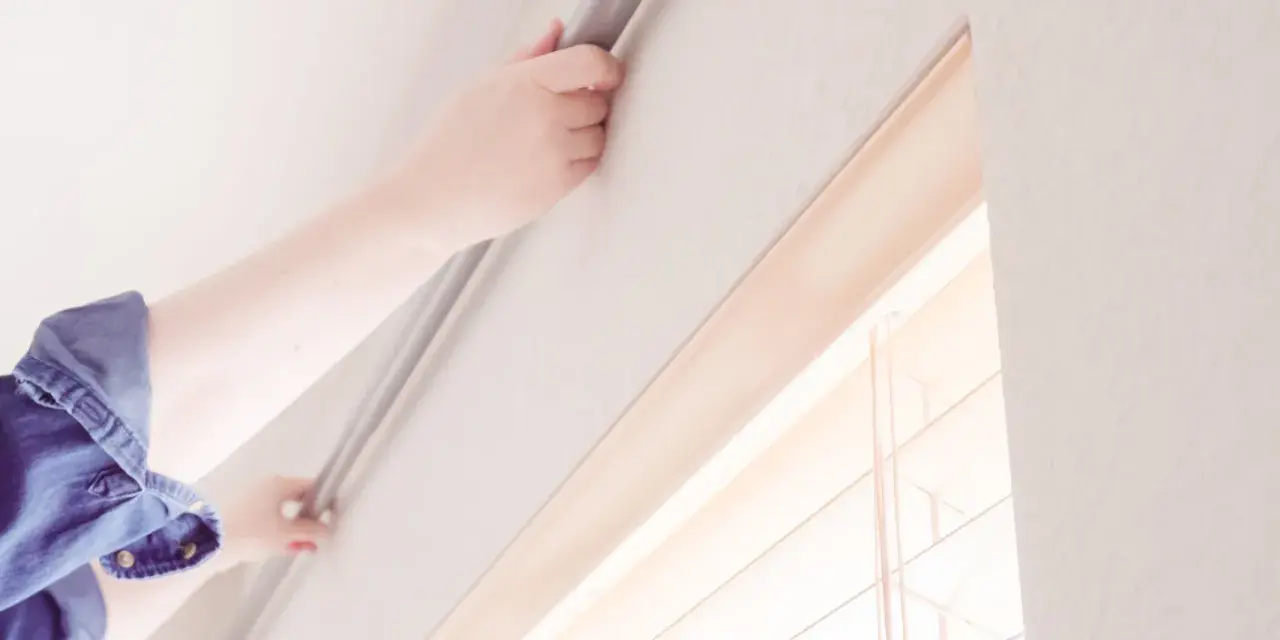 Hände befestigen eine Gardinenschiene an der Decke ohne Bohren. Einfache Montage für Ihre Fensterdekoration.