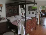 Ein prachtvolles Himmelbett im mittelalterlichen Stil, mit kunstvollen Schnitzereien und einem karierten Bettzeug.
