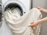 Helle Gardinen werden in die Waschmaschine geladen. Mit Backpulver werden sie wieder strahlend weiß.