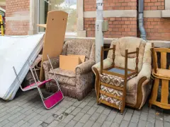 Alte Matratze entsorgen: Sperrmüll mit Sesseln und Holzmöbeln steht auf dem Gehweg.
