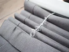 Grauer Raffrollo Stoff mit Schnüren und Ringen, bereit zum Raffrollo waschen.