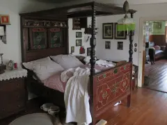 Ein prachtvolles Himmelbett im mittelalterlichen Stil, mit kunstvollen Schnitzereien und einem karierten Bettzeug.