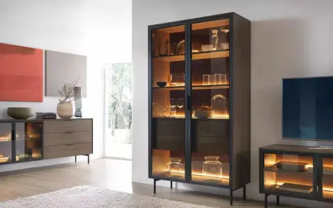 Beleuchteter Vitrinenschrank mit Gläsern und Dekoartikeln, daneben ein Sideboard.