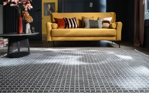 Ein gelbes Sofa mit Kissen steht auf einem gemusterten Teppich unter dem Sofa.