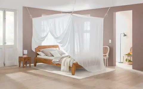 Ein gemütliches Schlafzimmer mit Himmelbett und Moskitonetz, das vor Elektrosmog schützt.