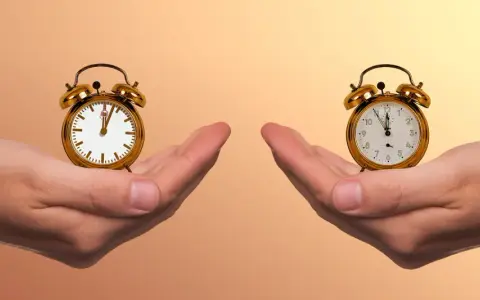 Zwei Hände halten je einen Wecker. Die Frage ist: wann aufstehen?