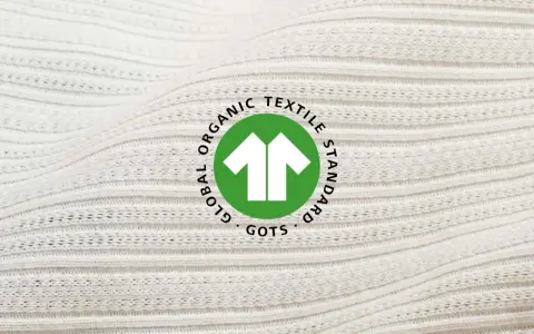 Das GOTS-Zertifikat auf weißem, geripptem Stoff. Es steht für Global Organic Textile Standard und garantiert nachhaltige Textilien.