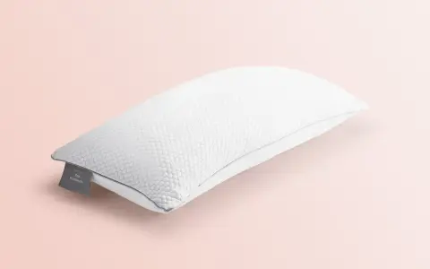 Ein weißes, wabenförmiges Kopfkissen liegt auf einem zartrosa Hintergrund. Perfekt für das Kopfkissen waschen, um Frische zu garantieren.