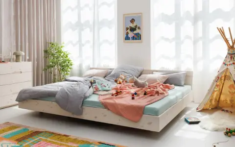 Ein gemütliches Familienbett mit Spielzeug und Kuscheltieren, das zum Kuscheln einlädt. Hier ist Platz für die ganze Familie.