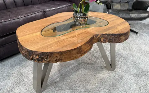 Ein Couchtisch aus massivem Holz mit Glasplatte und Metallbeinen. Die Höhe ist ideal, um Getränke und Snacks bequem zu erreichen.