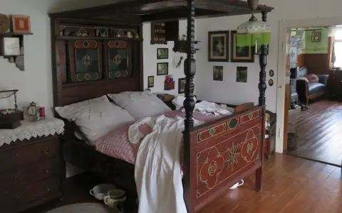 Ein prachtvolles Himmelbett im mittelalterlichen Stil, mit kunstvollen Schnitzereien und einem karierten Bettzeug.