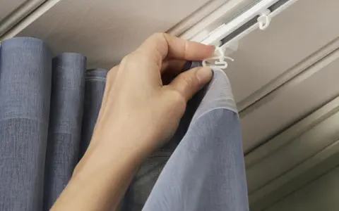 Hand befestigt Gardinenband Haken an der Gardinenschiene. So hängen die Vorhänge perfekt.
