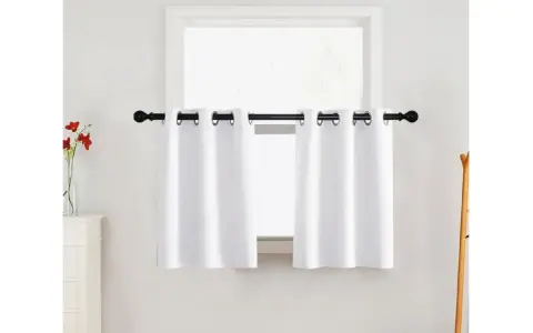 Zwei weiße Ösen-Gardinen hängen an einer schwarzen Stange vor einem Fenster. Diese Gardinenarten sind praktisch und stilvoll.