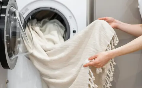 Helle Gardinen werden in die Waschmaschine geladen. Mit Backpulver werden sie wieder strahlend weiß.