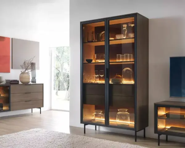 Beleuchteter Vitrinenschrank mit Gläsern und Dekoartikeln, daneben ein Sideboard.