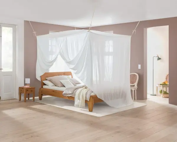 Ein gemütliches Schlafzimmer mit Himmelbett und Moskitonetz, das vor Elektrosmog schützt.