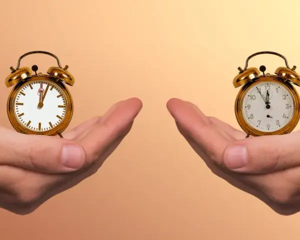 Zwei Hände halten je einen Wecker. Die Frage ist: wann aufstehen?