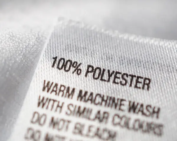 Etikett zeigt "100% POLYESTER". Dieser Stoff ist pflegeleicht und ideal für Kleidung, die oft gewaschen wird.