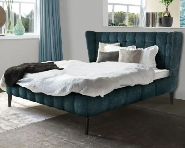 Ein luxuriöses Bett mit tiefblauem Polster und weißen Bettwäsche-Ideen. Dekorative Kissen und eine dunkle Decke laden zum Entspannen ein.