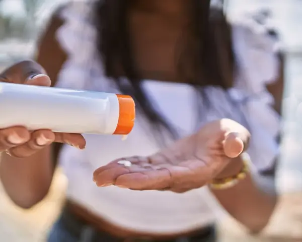 Frau gibt Sonnencreme auf ihre Hand. So vermeidet sie Sonnencreme Flecken auf Kleidung.