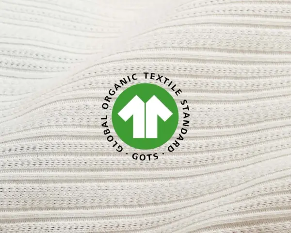 Das GOTS-Zertifikat auf weißem, geripptem Stoff. Es steht für Global Organic Textile Standard und garantiert nachhaltige Textilien.