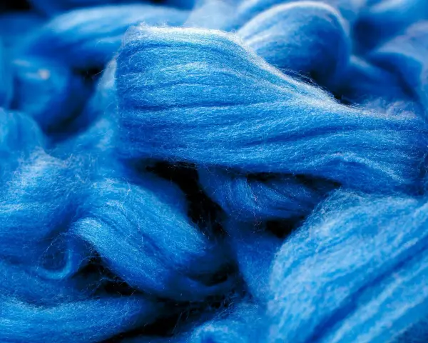 Leuchtend blaue Fasern, die an Wolle erinnern. Obwohl sie sich wie eine Naturfaser anfühlt, ist Viskose eine künstlich hergestellte Faser.